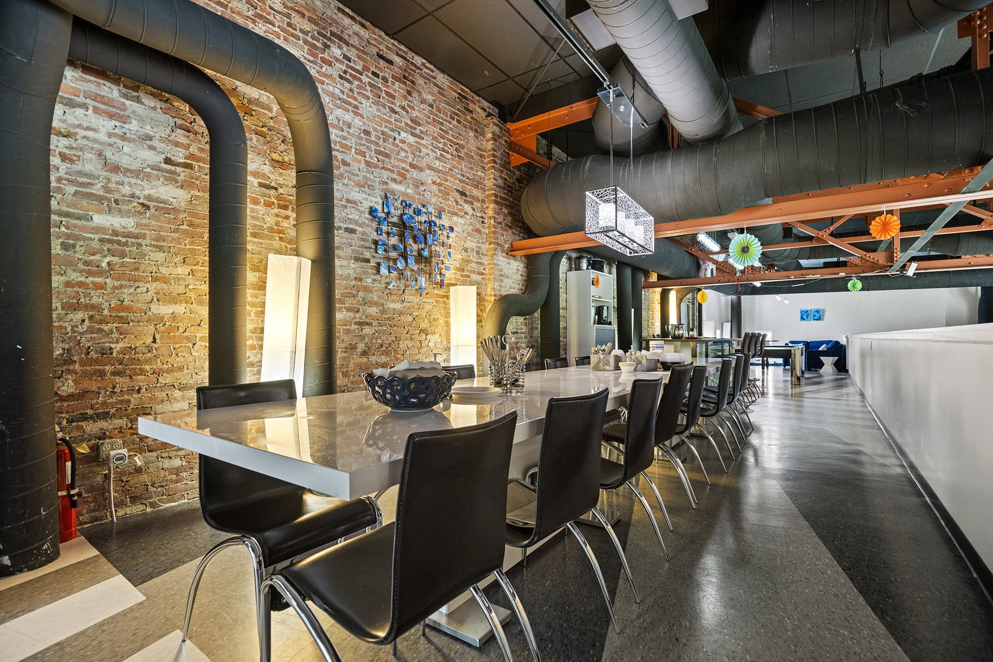 Modern conference room with brick wall, black chairs, and industrial ceiling design.