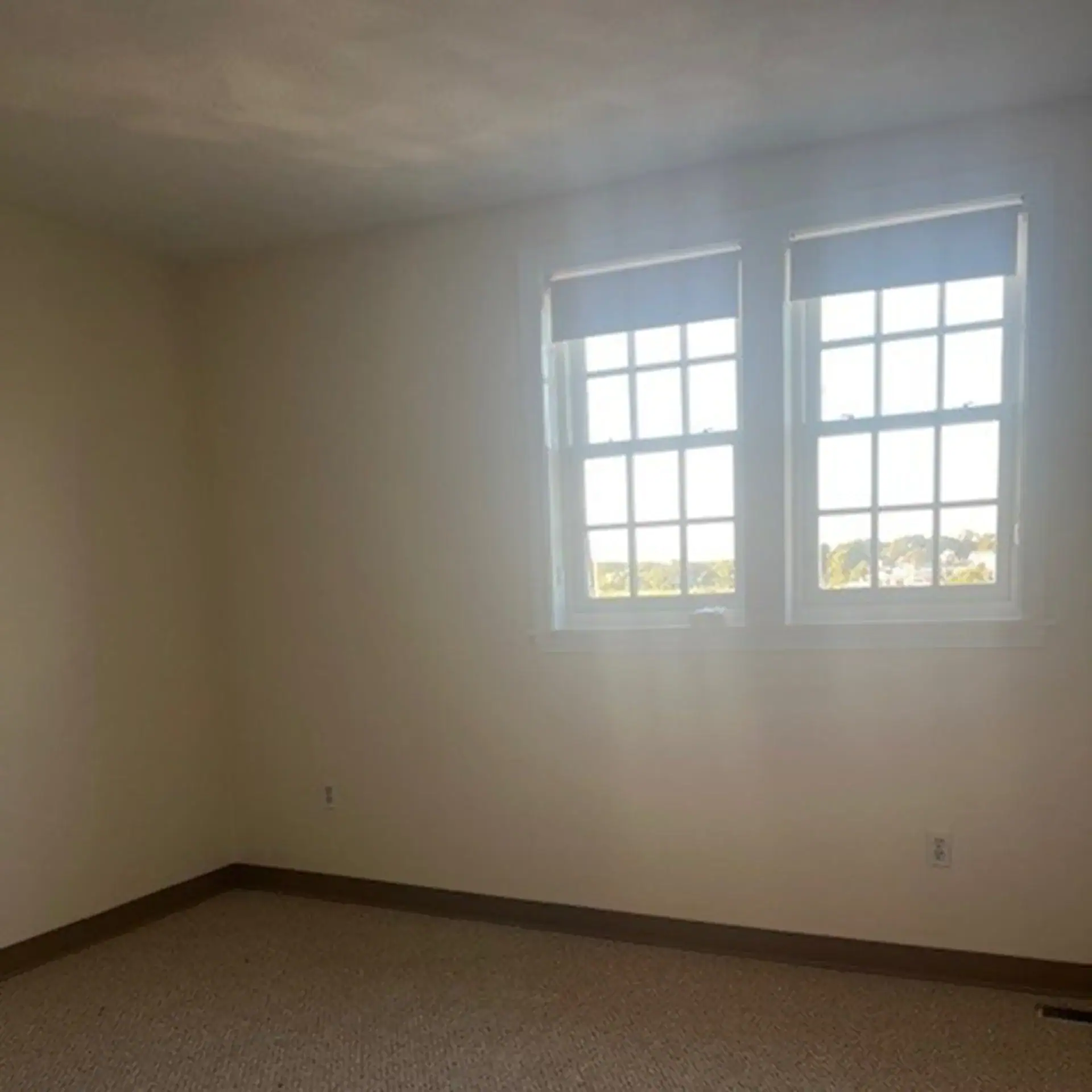 Empty room with two large windows and beige walls in Newburyport.