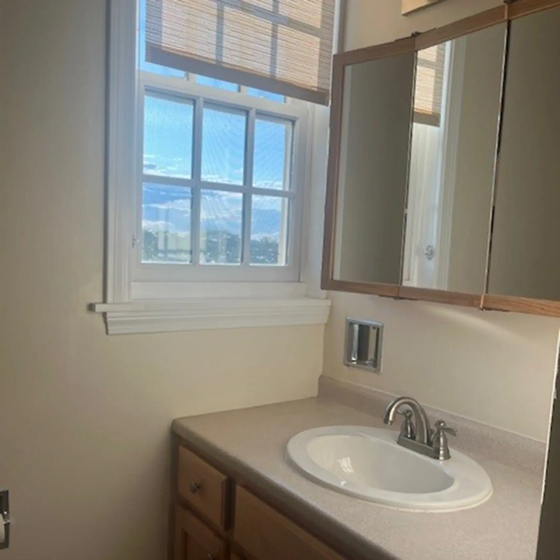 Bathroom with window, mirror, and sink with faucet.