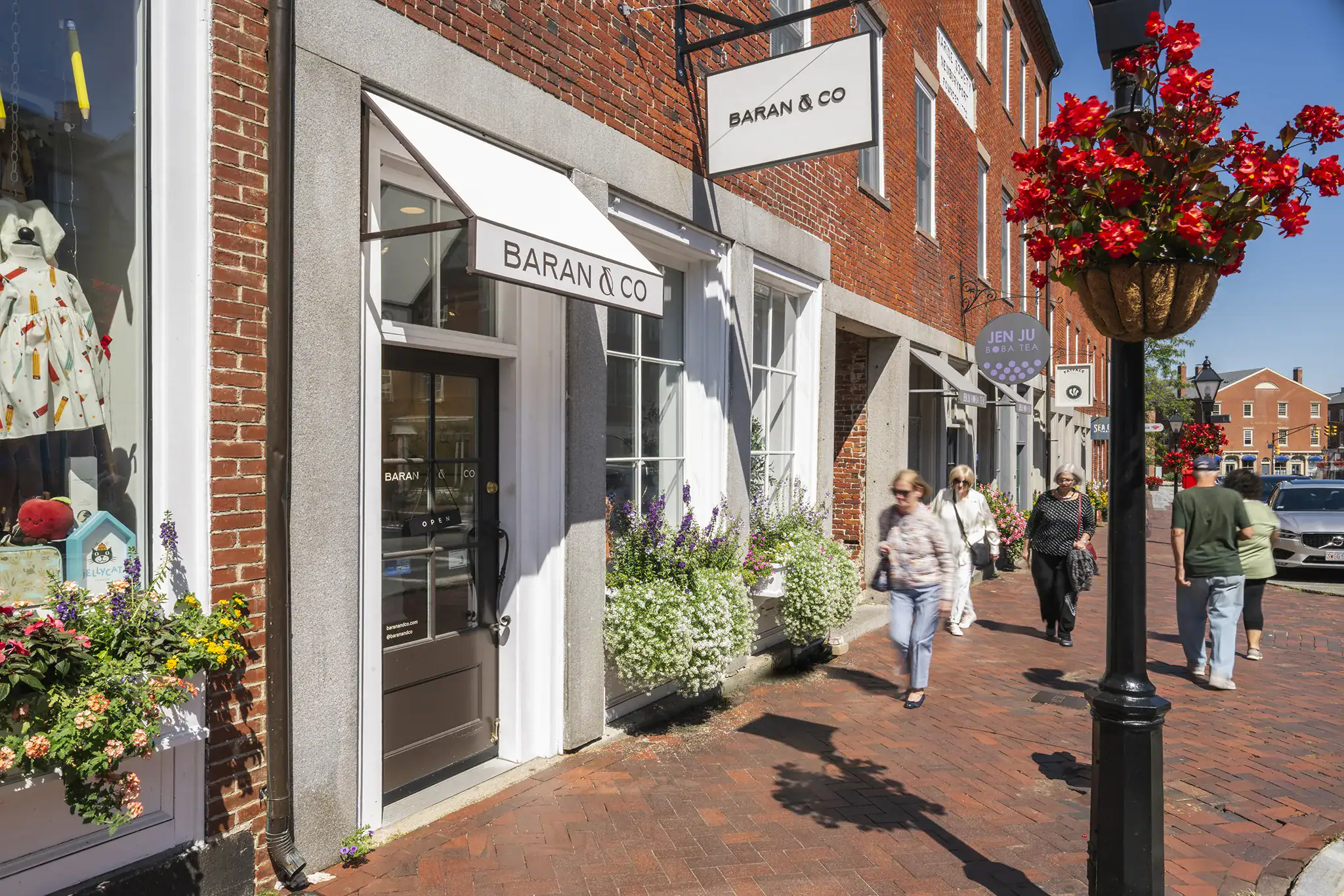 People walking past Baran & Co storefront on a sunny day in Newburyport.