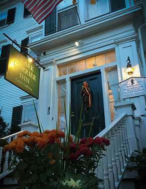 Exterior view of the Rockporter Inn with flowers and a sign at dusk.