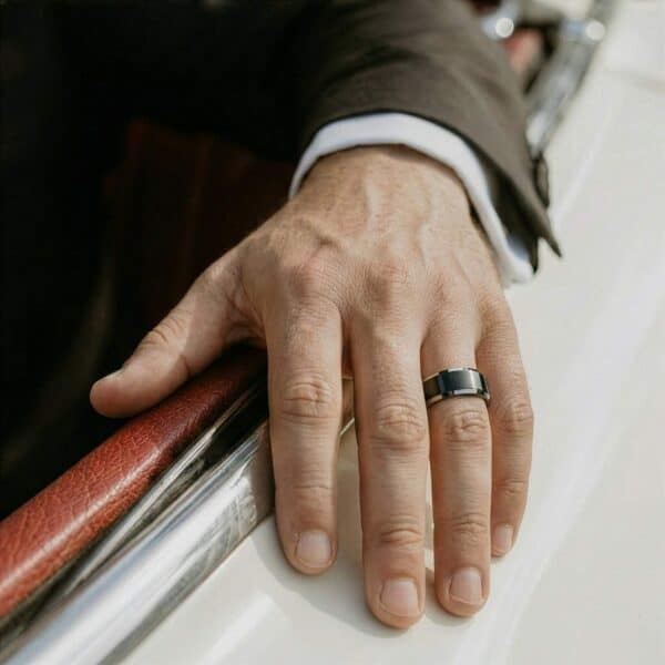 Resting his arm out of the car window, the mans hand is on display, showing his black and silver tungsten ring.