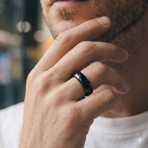 A close-up image of a man who has his hand held up to his chin. He is wearing a black tungsten ring that looks like a mans wedding ring. It is slightly domed in shape and is highly polished.