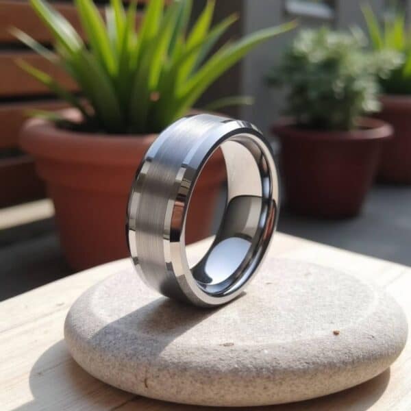 Amongst the plant pots, this silver tungsten ring stands upright, balanced on top of a pebble. This silver tungsten ring has a brushed section at its centre and polished silver edges.