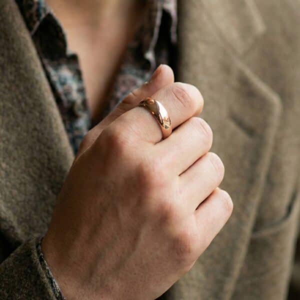A close up of a man wearing a polished rose gold tungsten ring.