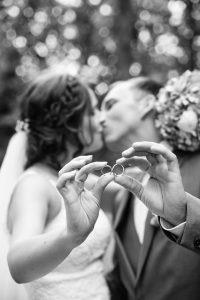 Married couple kiss as they hold out their wedding rings
