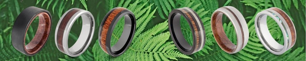 Selection of natural wood rings for men against backdrop of lush green fern leaves