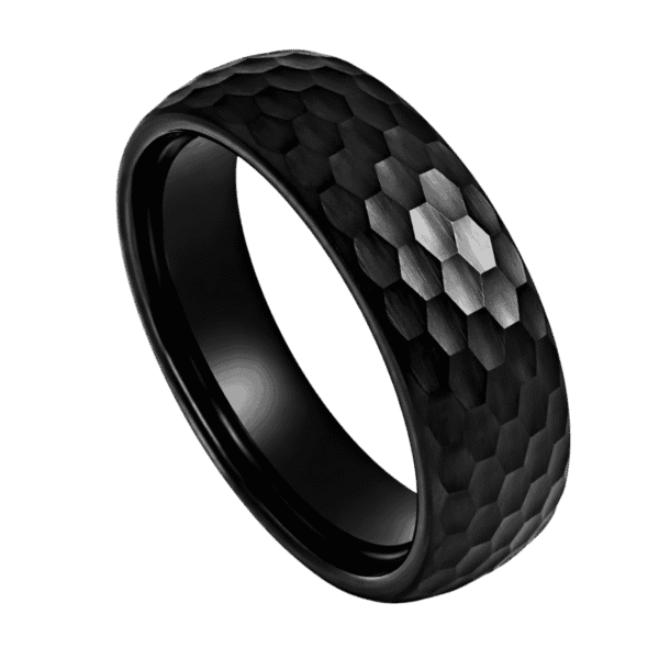 A close up image of a mans black ring. Made with tungsten, this black ring has a hammered effect finish. This means that the ring catches the light from many different angles.