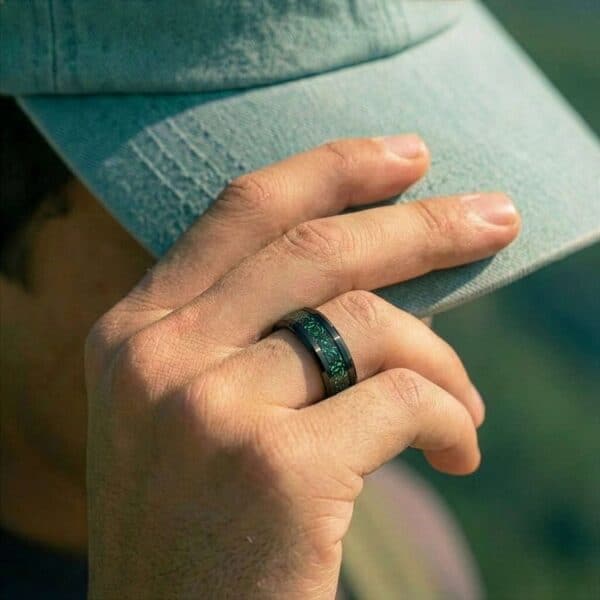 Pulling down his green cap to keep the sun out of his face, the mans hand is on display showing his green and black ring made with carbon and tungsten.