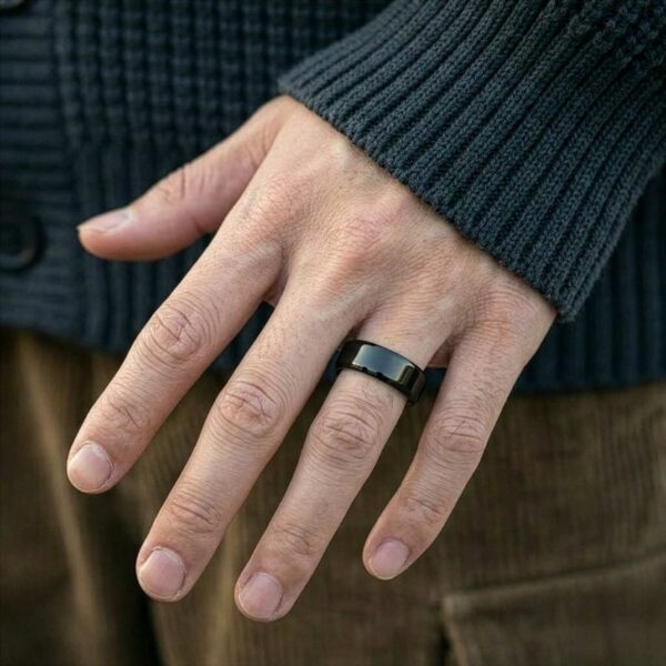 A mans hand is in full view, showing that he is wearing a polished black tungsten ring that is flat in style.