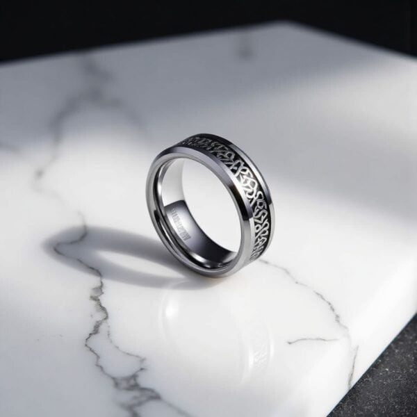 Sterling silver wedding band with intricate Celtic-inspired design, resting on a marble surface. Perfect for engagements or as a symbol of eternal love. Handcrafted craftsmanship with detailed engravings.