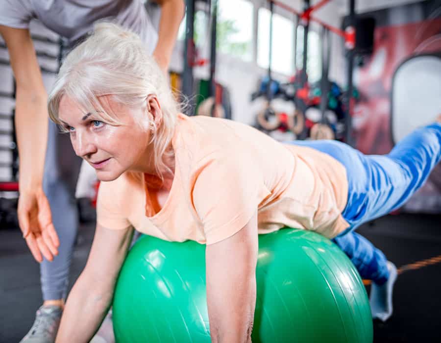 Senior woman doing physical therapy exercise with a stability ball at North Platte PT.