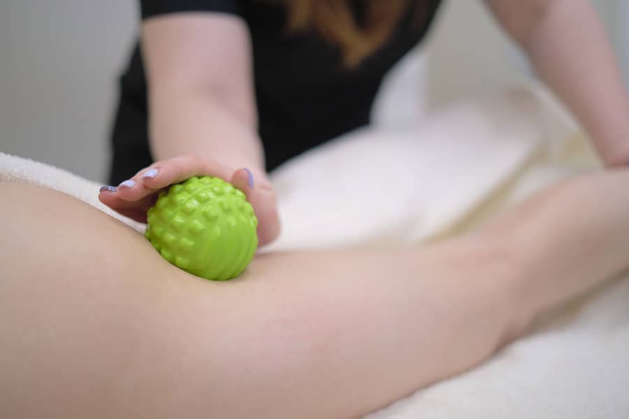 Therapist performing myofascial release with a green massage ball.