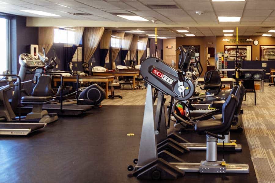 Well-equipped physical therapy gym with exercise machines and therapy tools.