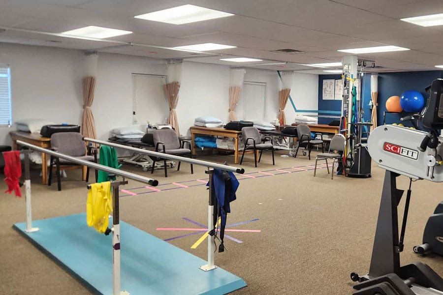 Physical therapy rehabilitation room with parallel bars and exercise equipment.