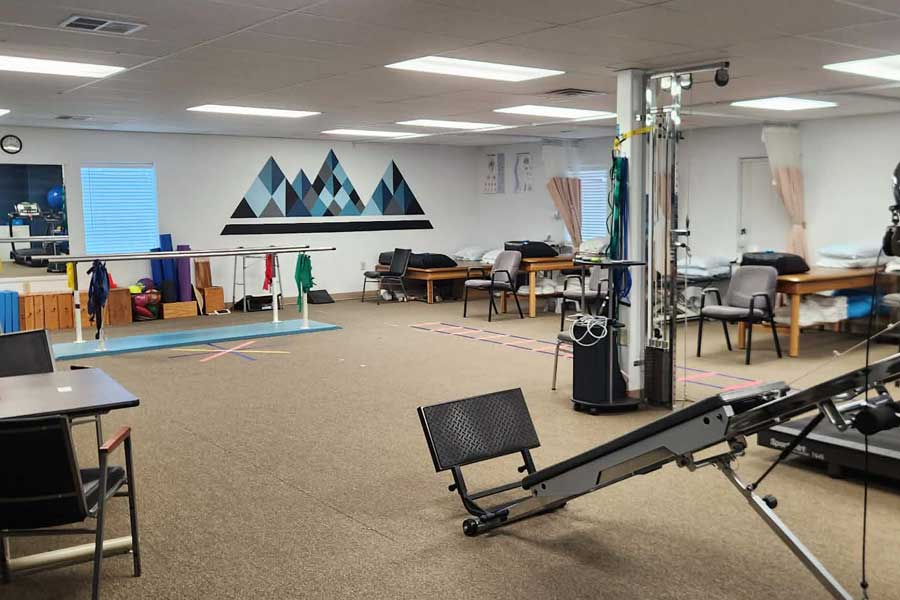 Physical therapy treatment room with equipment and therapy tables.