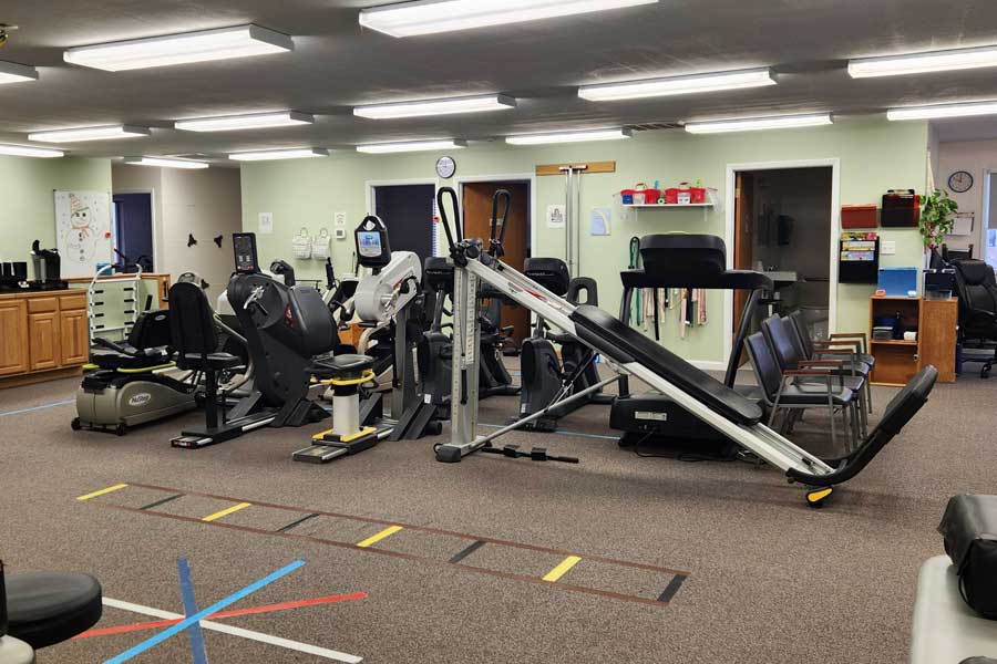Physical therapy gym with exercise equipment and therapy tools.