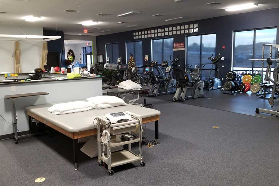 Physical therapy clinic with treatment table and exercise equipment.