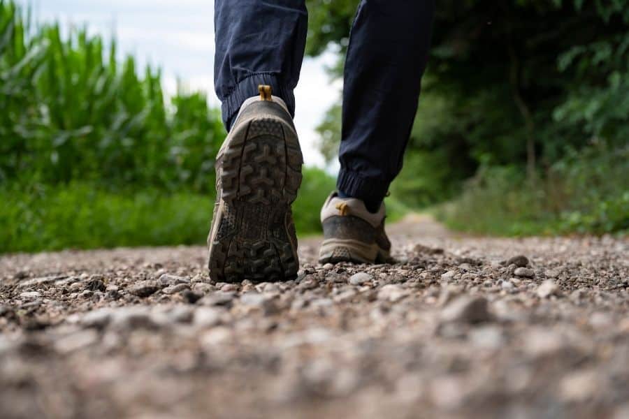 Close-up of a person walking on a gravel trail in nature.
