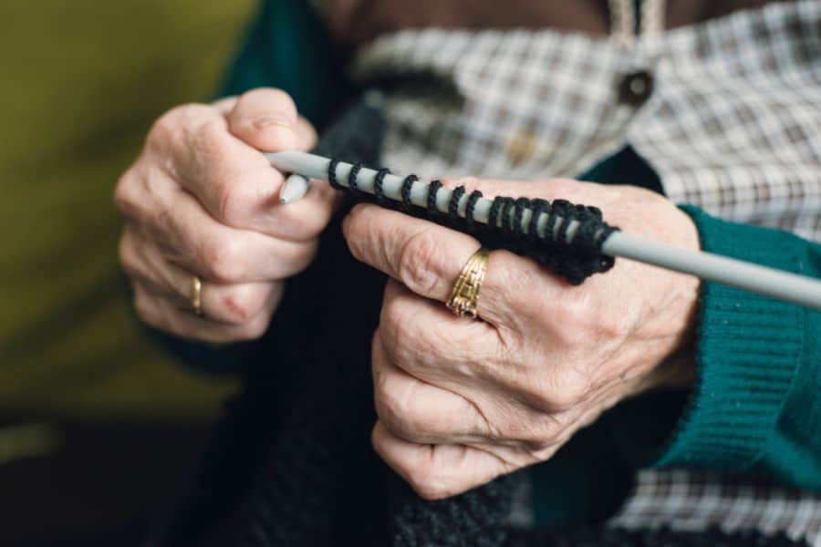 Elderly person practicing fine motor skills with a therapy tool.