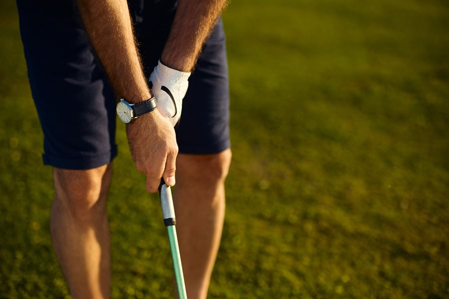 Person practicing golf swing on a lush green course.