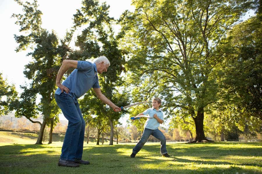 Elderly man and young boy practicing physical therapy outdoors in a park.