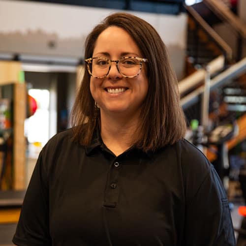Smiling woman in black polo at North Platte Physical Therapy clinic.