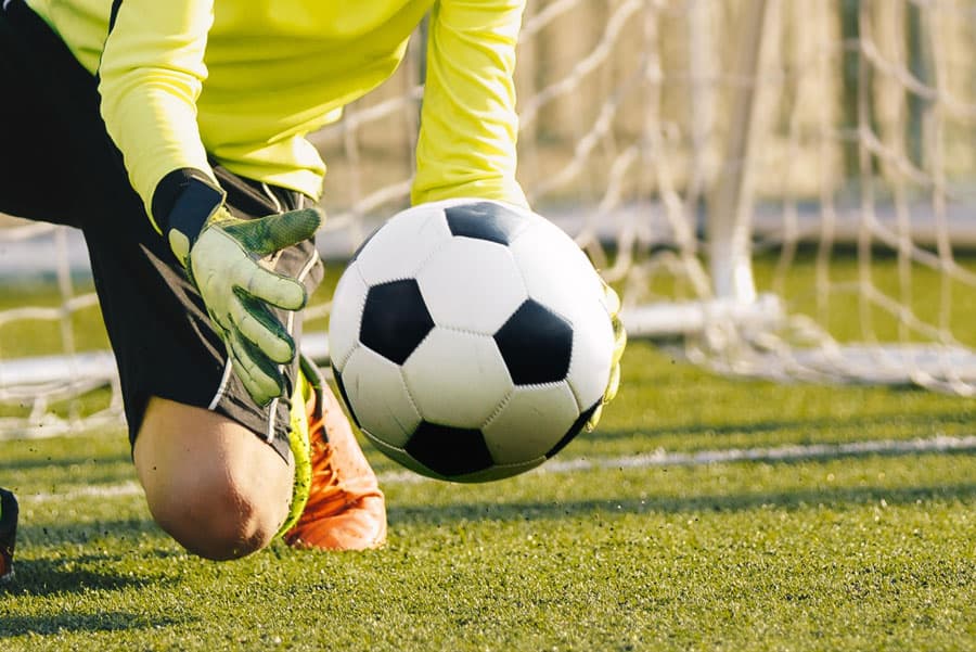 Youth soccer goalkeeper practicing save on field.