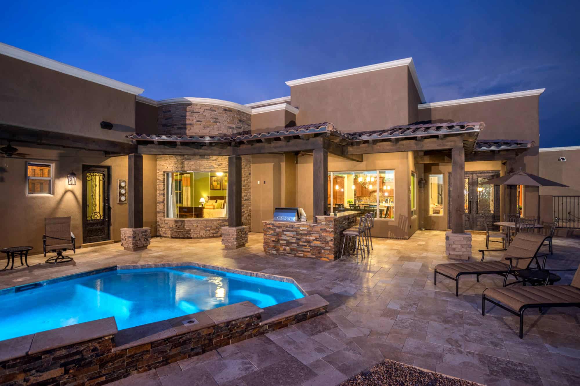 Night view of exquisite tiled back patio and lighted swimming pool.