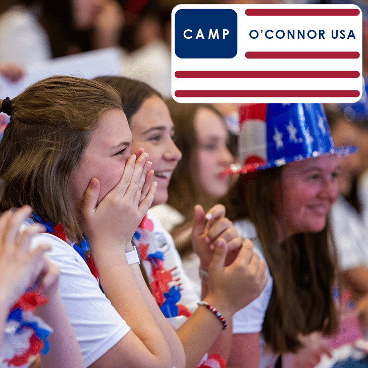 A group of smiling girls wearing red, white, and blue accessories clap and cheer at a Youth Programs event. In the top right corner, a logo reads "CAMP O'CONNOR USA" with stylized red and blue stripes.