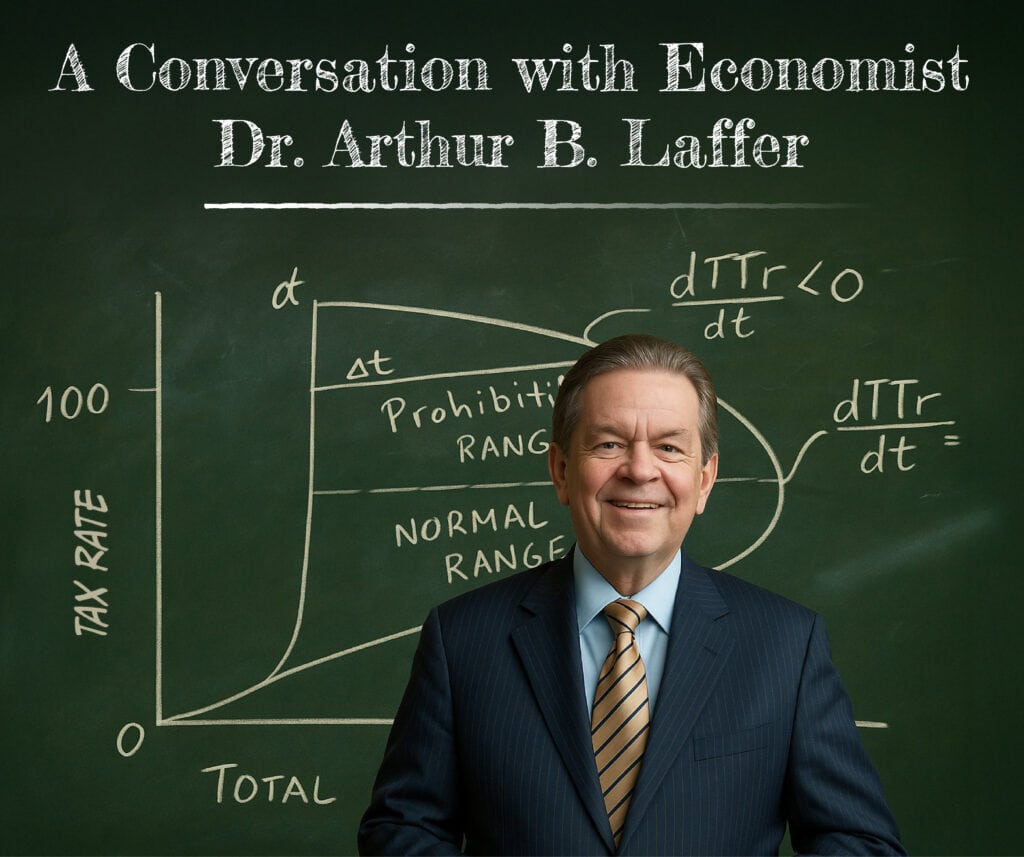 A smiling man in a suit stands in front of a chalkboard with economic graphs and formulas. Text above reads, “A Conversation with Economist Dr. Arthur B. Laffer.”.
