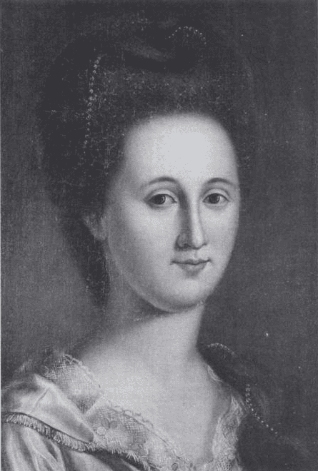 Black-and-white portrait of a woman with an elaborate hairstyle, wearing a dress with lace trim. In honor of Women's History Month, she looks directly at the viewer with a calm expression against a plain background.