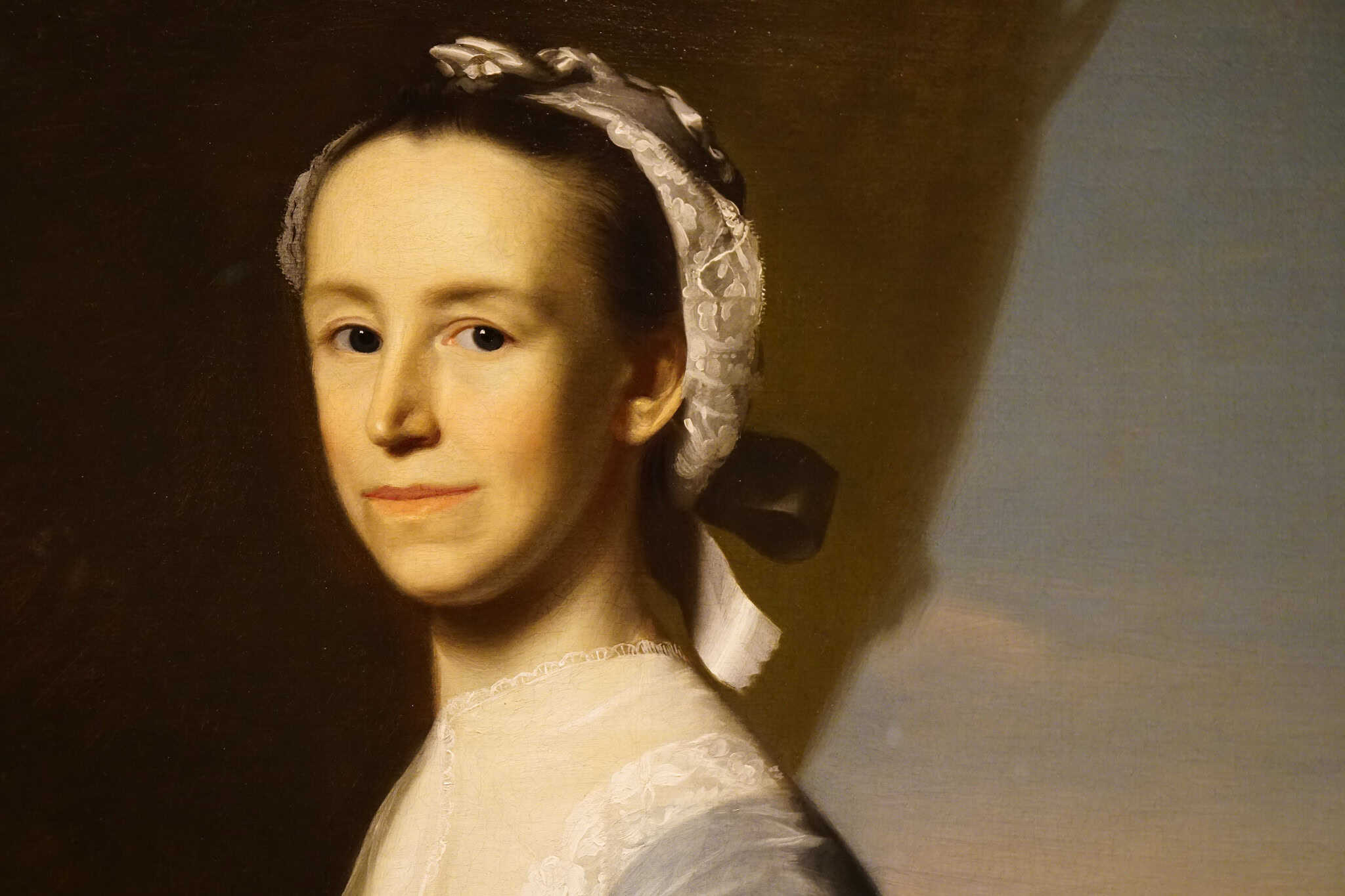 A classical oil portrait of a woman with fair skin, wearing a white lace cap and dress with a black ribbon—her slight smile and poised look evoke the dignified spirit often celebrated on Constitution Day, set against a neutral background.