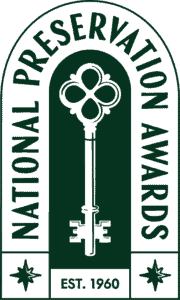 A logo featuring a large ornate key in the center, surrounded by the words “National Preservation Awards.” At the bottom, it says “EST. 1960” with a small star or decorative element on each side.