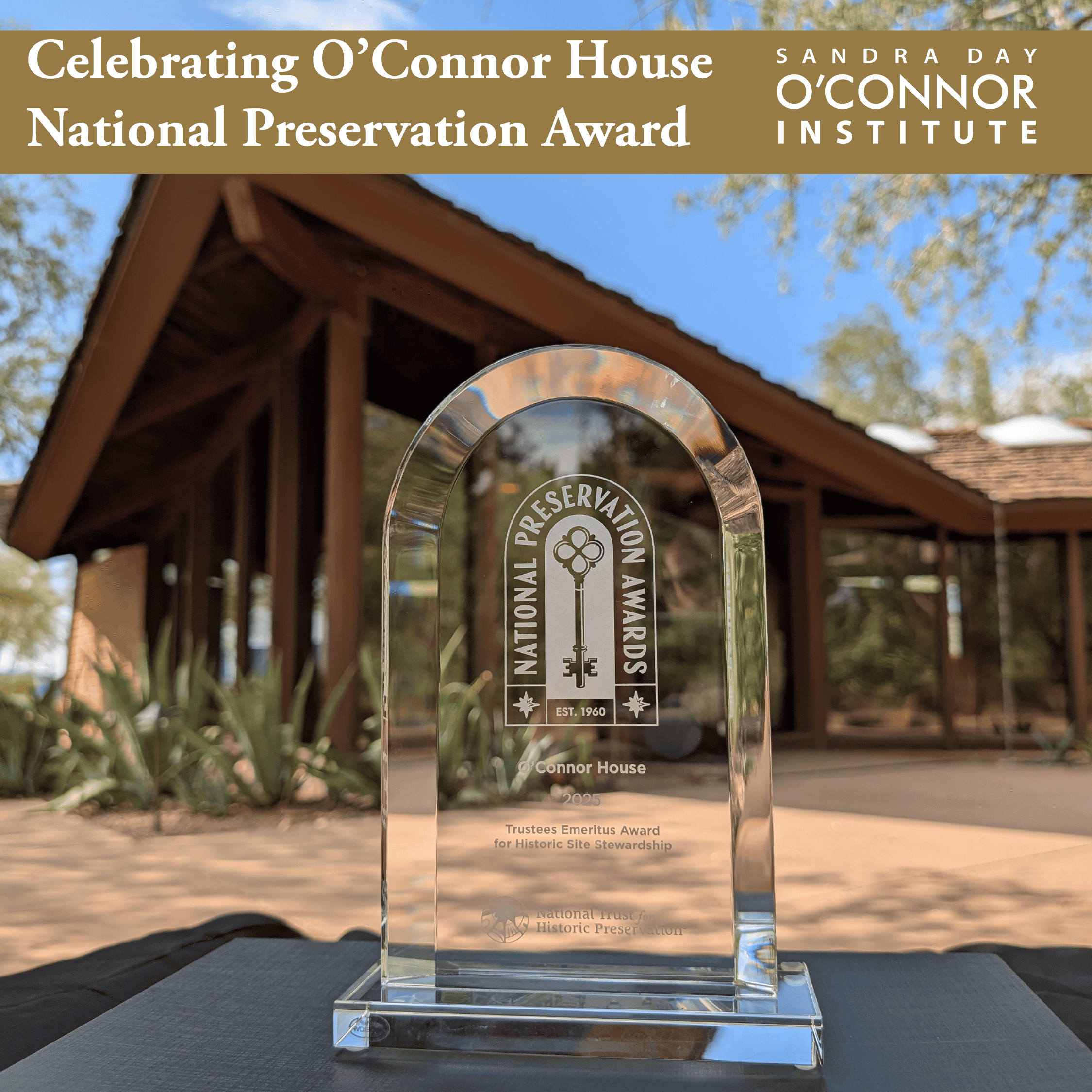 A glass National Preservation Award trophy sits on a table outdoors, with The Citizen and the O’Connor House framed by trees in the background. Text above reads “Celebrating O’Connor House National Preservation Award.”.