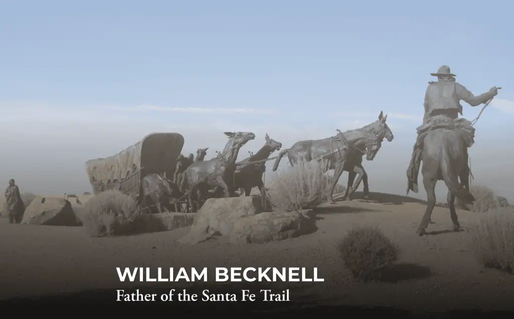 Bronze statues of a pioneer with a wagon and horses on a dirt path. Text reads: “WILLIAM BECKNELL Father of the Santa Fe Trail.” Bushes and a hazy blue sky are in the background.