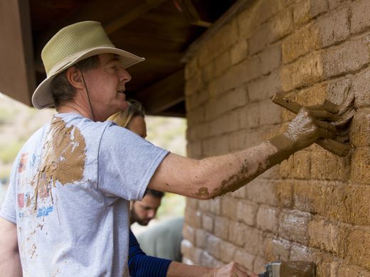 Former Tempe Mayor Hugh Hallman applies mud to the side of the O'Connor House as part of the mudsling in 2017.