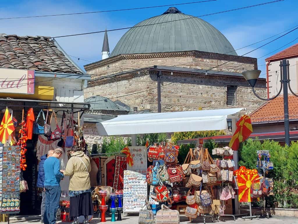 stalls in the Old Bazaar in Skopje, including bags, fridge magnets, flags and other souvenirs with Čifte Hammam, Old Bathhouse in the background