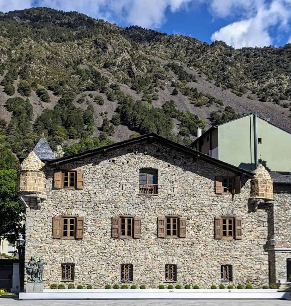 Casa de la Vall - the parliament building until 2011 with a mountain background. Visit this as one of the main things to do in Andorra La Vella