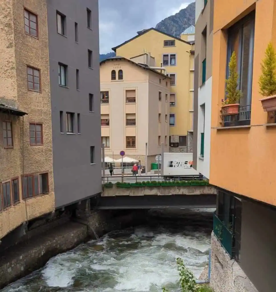 View from Pont d'Engordany of the rushing water, buildings and mountains in Andorra La Vella