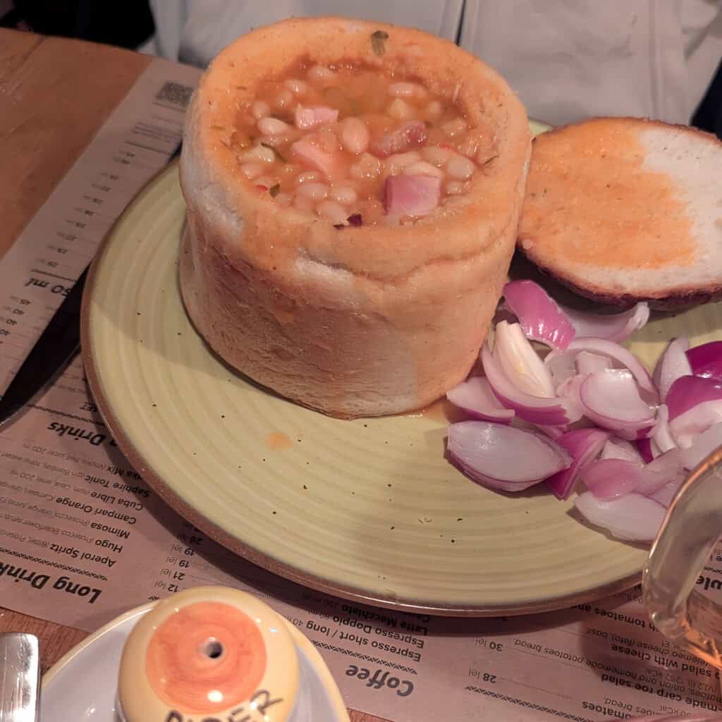 La Ceaun signature cauldron dish. Bean stew with ham in bread pot and red onions
