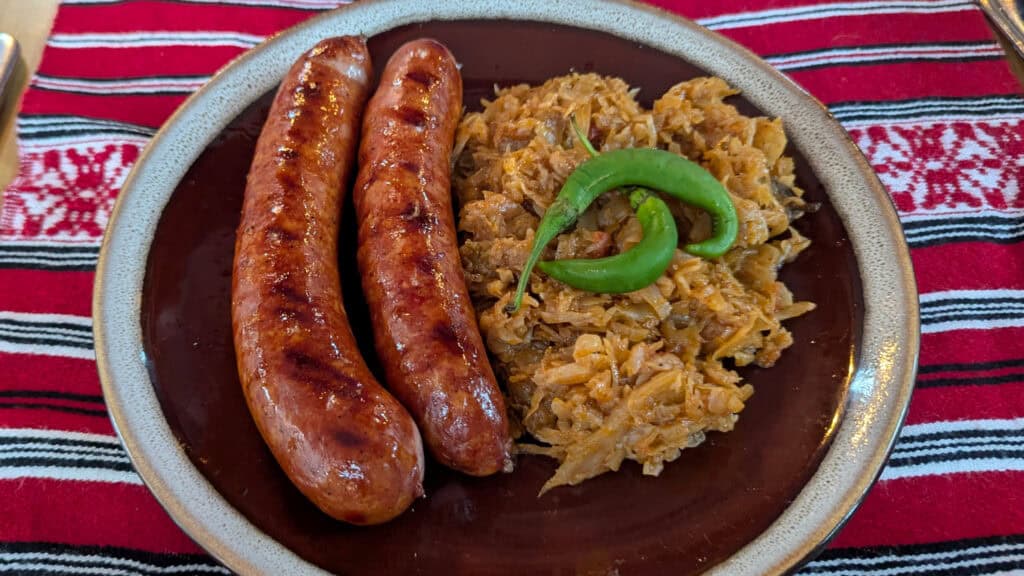 Traditional Romanian Food at Ceasu Rau Brasov Mici alongside varza călită - braised stewed sauerkraut