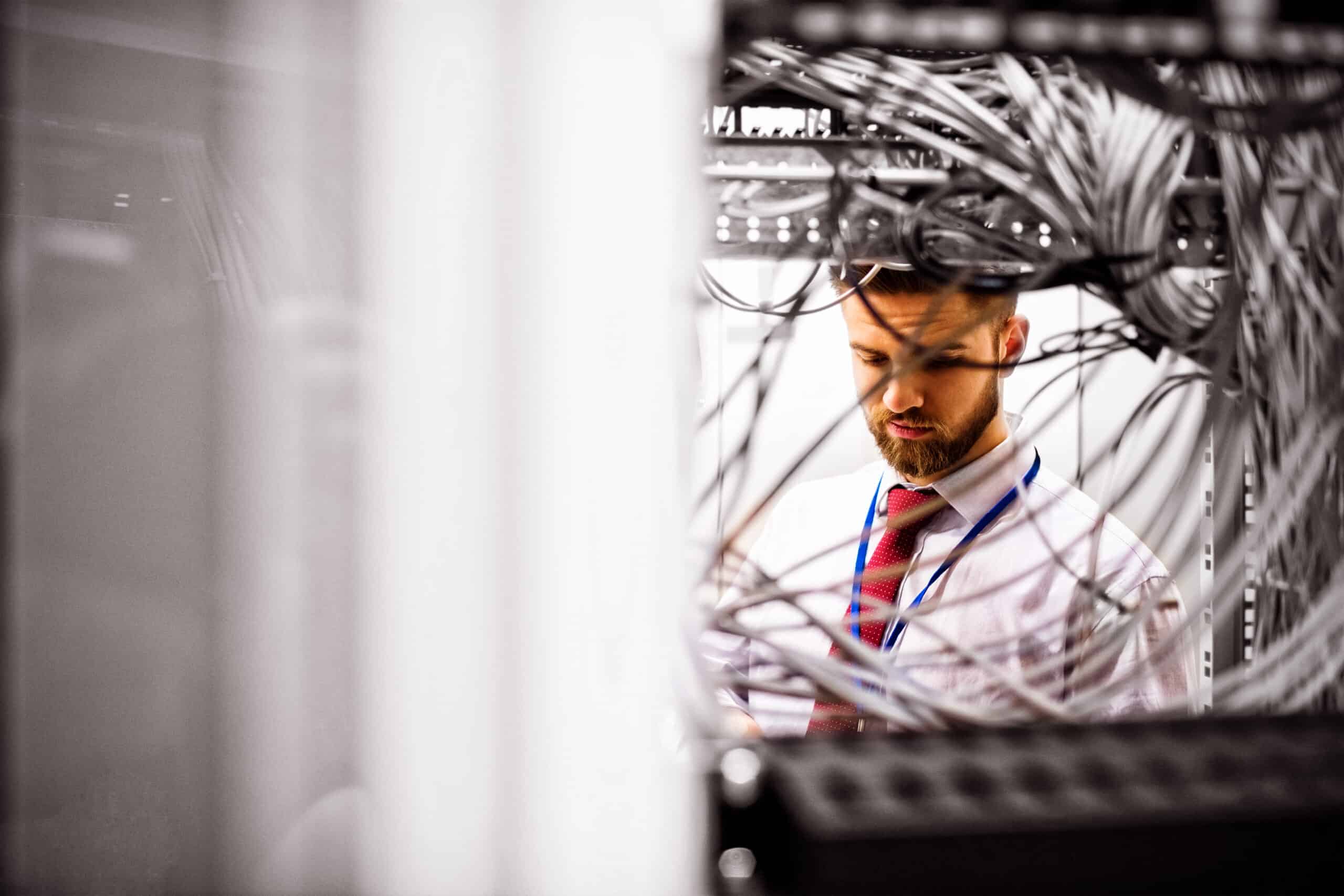 Server technician working on networking equipment in data center.