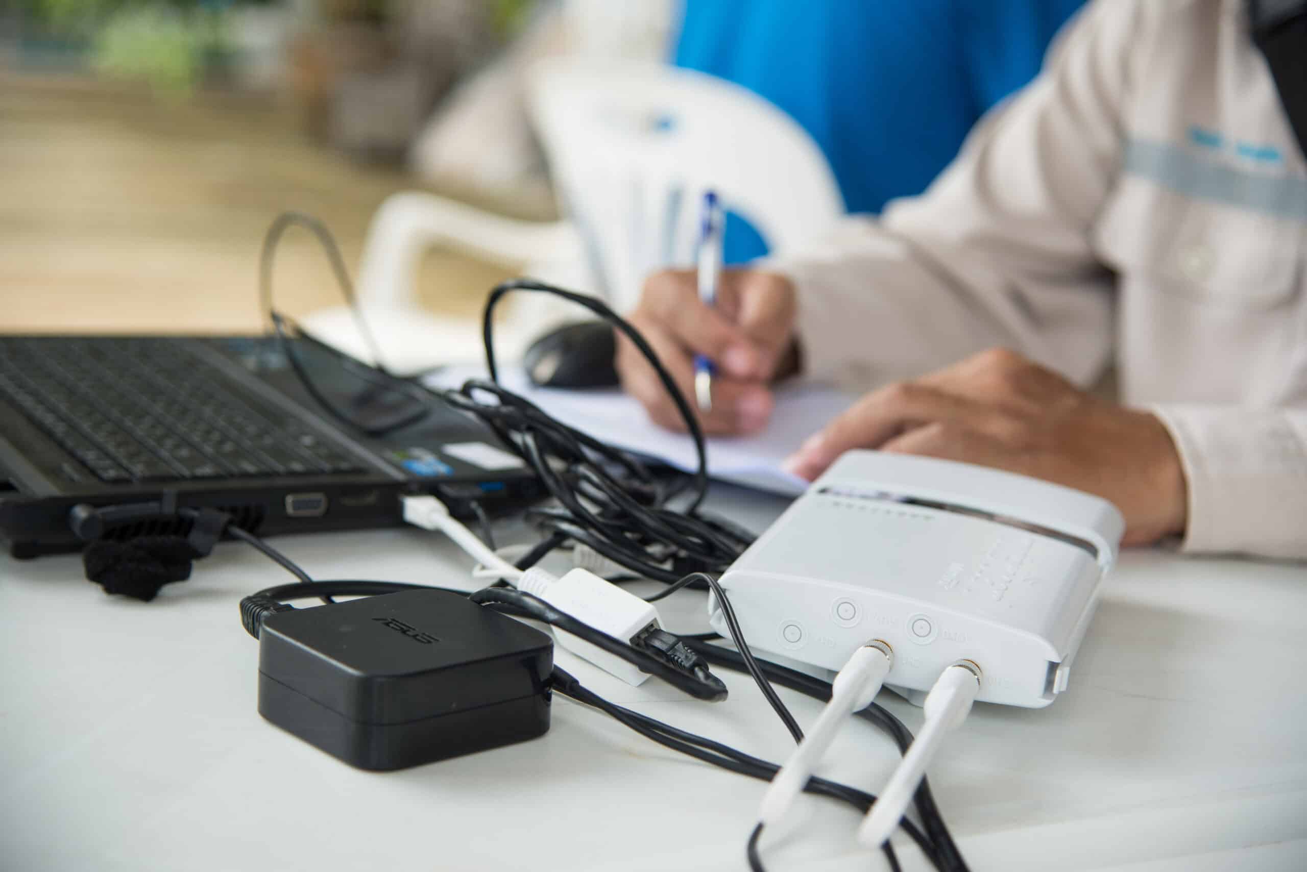 Modern Wi-Fi router connected to laptop and networking devices on desk.