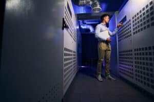 Data center technician managing server rack in a high-tech facility.