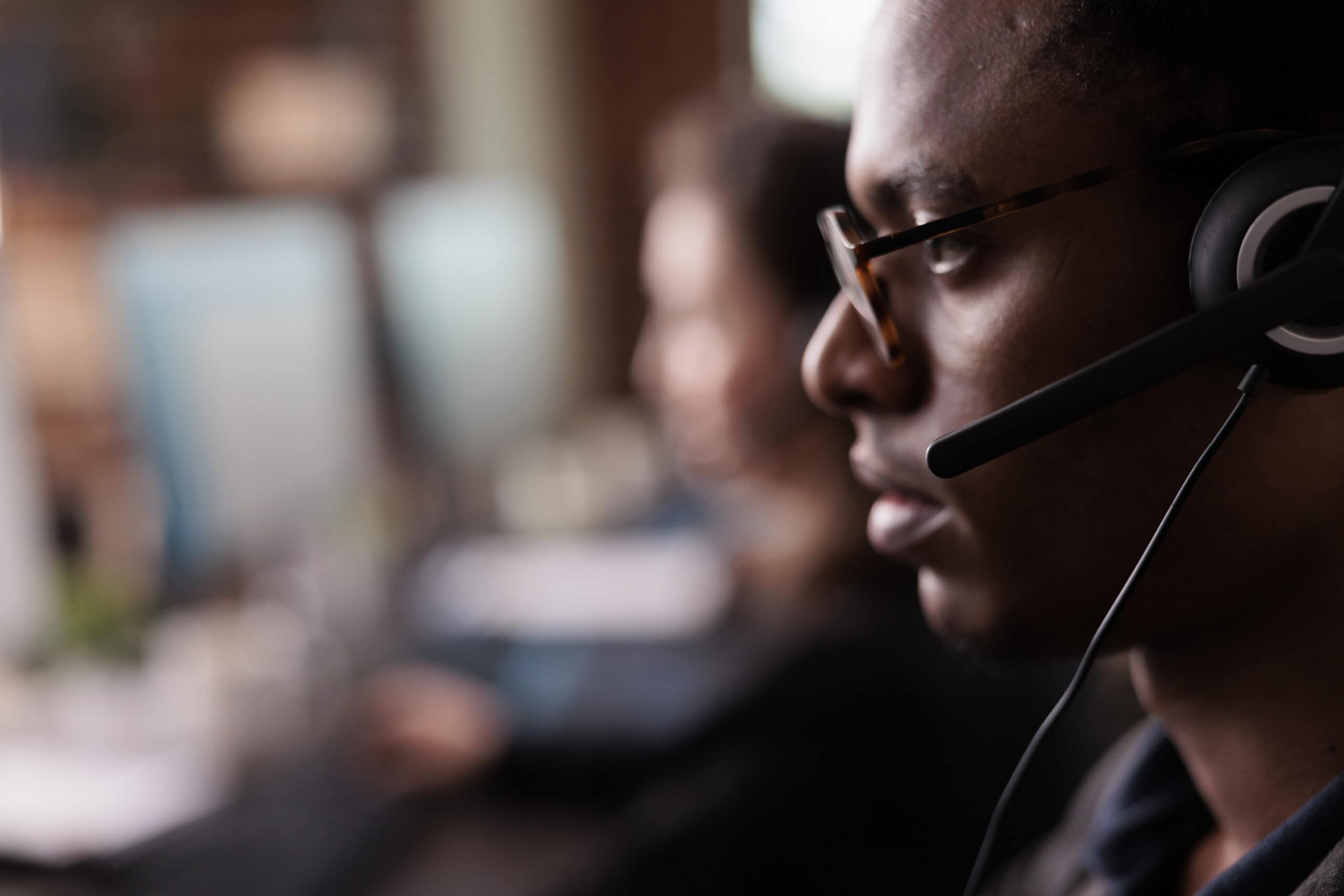 Customer service representative wearing headset and glasses at work.