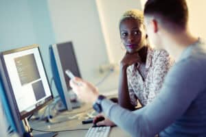 Diverse women collaborating at a computer in an office setting.