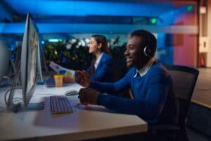 Friendly man with headphones working at computer in modern office.