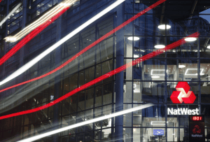 A modern office building with the NatWest logo and light trails from passing vehicles.