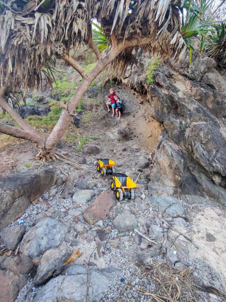 Climbing rocky coastal area with children and toy trucks.